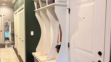 A hallway with a built-in bench, a door, and a mirror.