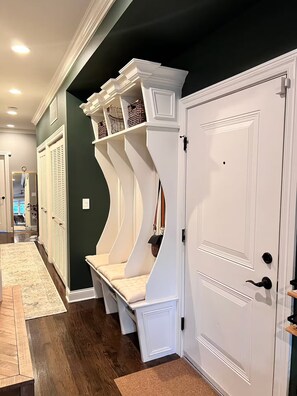 A hallway with a built-in bench, a door, and a mirror. - Luxurious Retreat: 3-Bed/3-Bath Condo (Chicago)