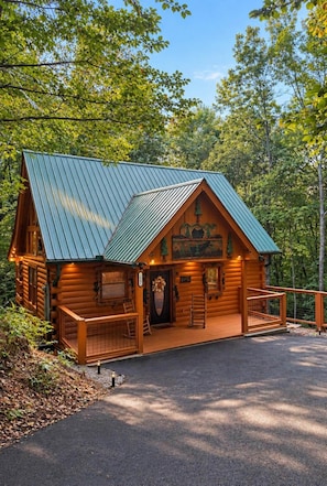 A log cabin with a metal roof, a front porch, and a decorative front door. - A Piece of Paradise| Pigeon Forge Cabin| Hot Tub (Sevier County)