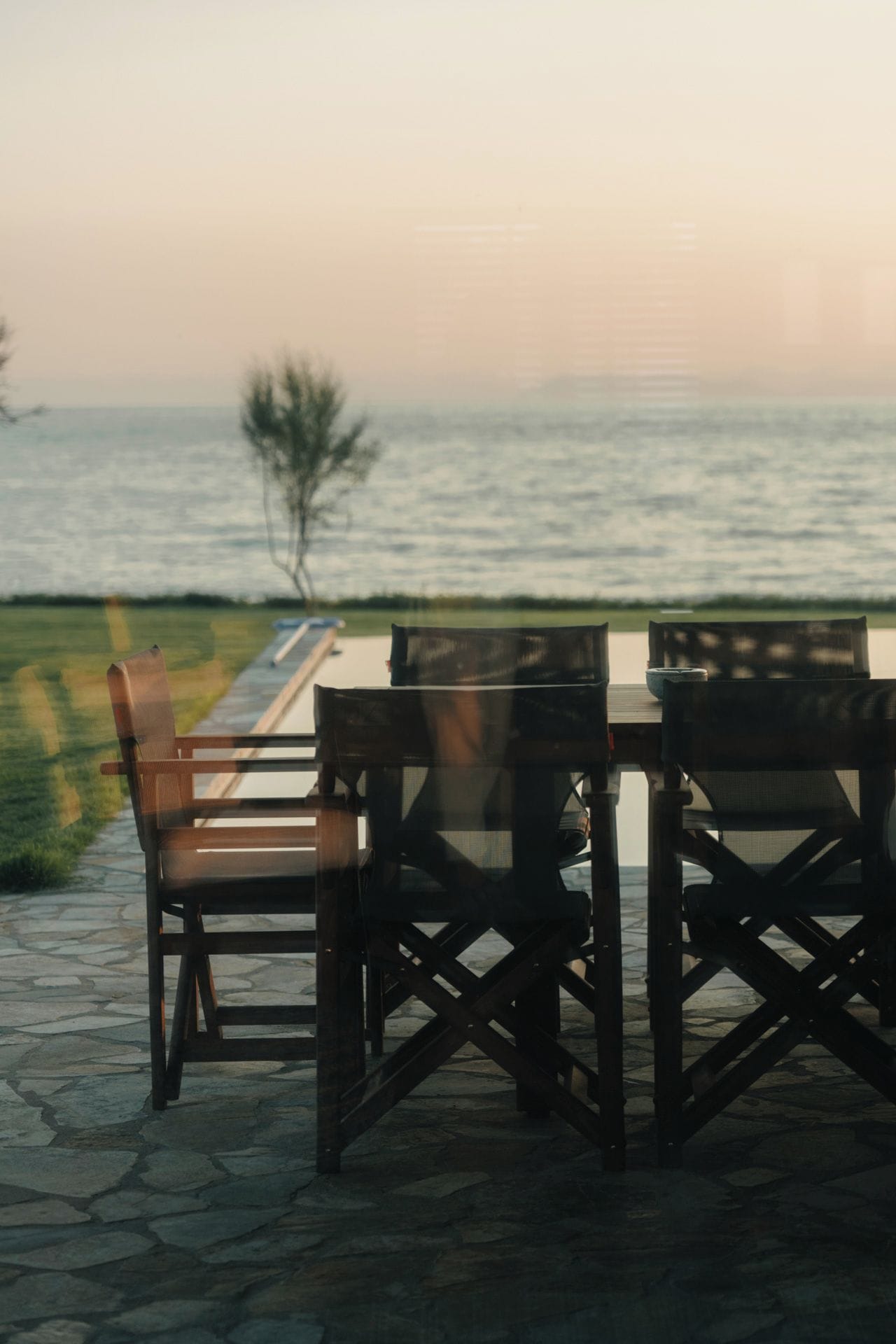 Una mesa y sillas sobre un patio de piedra con vista al mar.