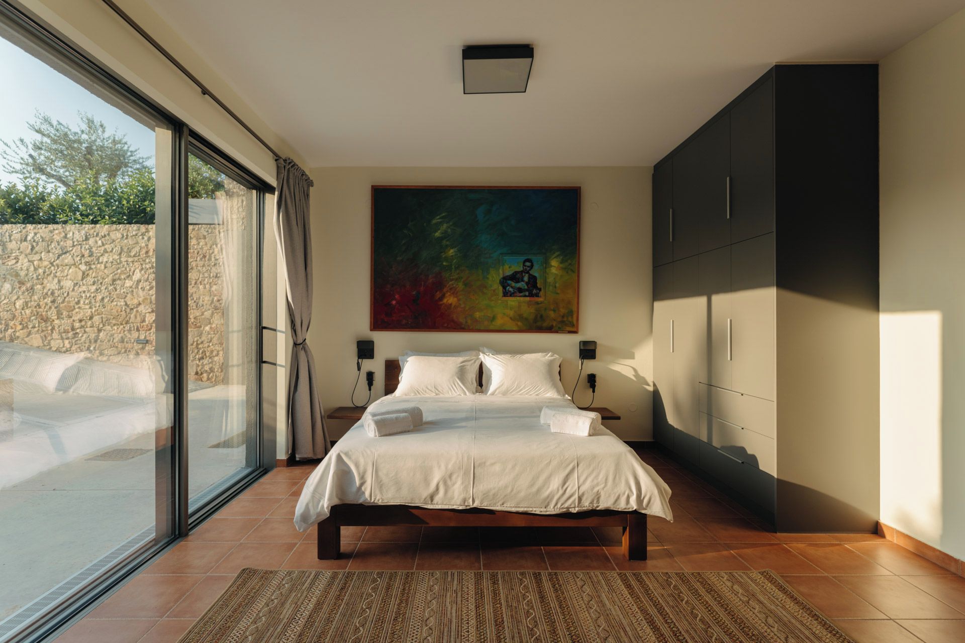 Une chambre à coucher avec un grand lit, un tableau au mur et une armoire.