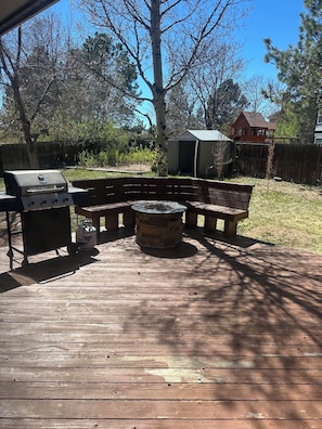 An outdoor deck with a grill, a fire pit, and a bench.