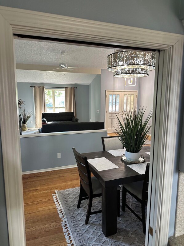 A dining area with a dark wooden table, chairs, and a potted plant.