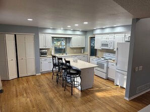 A kitchen with white cabinets, a central island with bar stools, and built-in appliances.