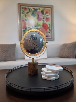 Un globe posé sur un support avec une base en bois, placé sur un plateau noir avec des objets rectangulaires blancs.