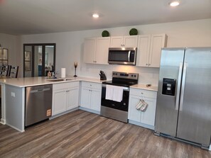 A modern kitchen with stainless steel appliances, white cabinetry, and a wooden floor. - NEW corner lot FURNISHED 3 BR, 2.5 bath townhouse N Raleigh w/security/Internet. (Raleigh)