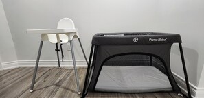 A baby changing station with a high chair and a portable playpen.