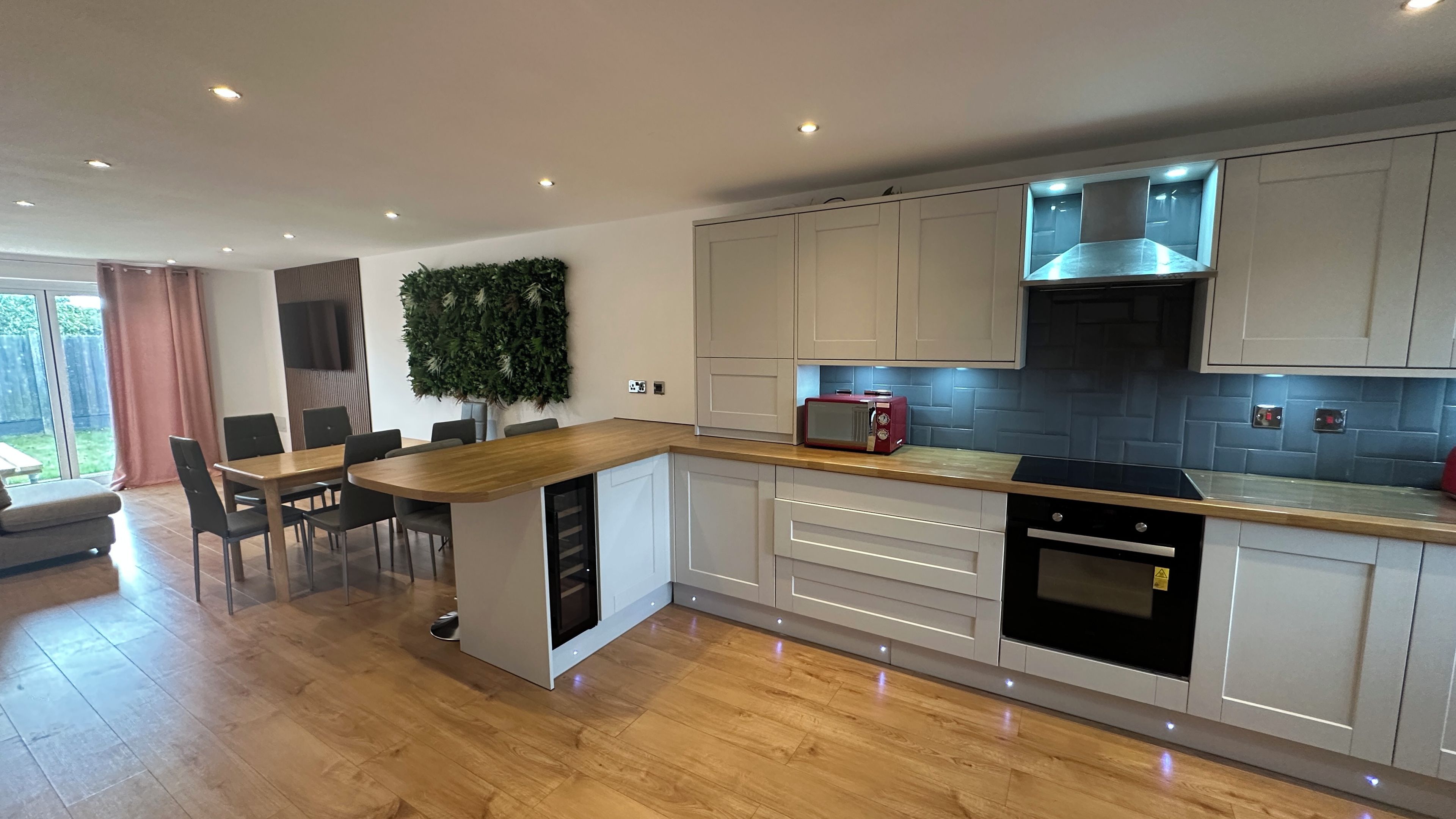 A modern kitchen with a central island, built-in appliances, and a dining area with a view.