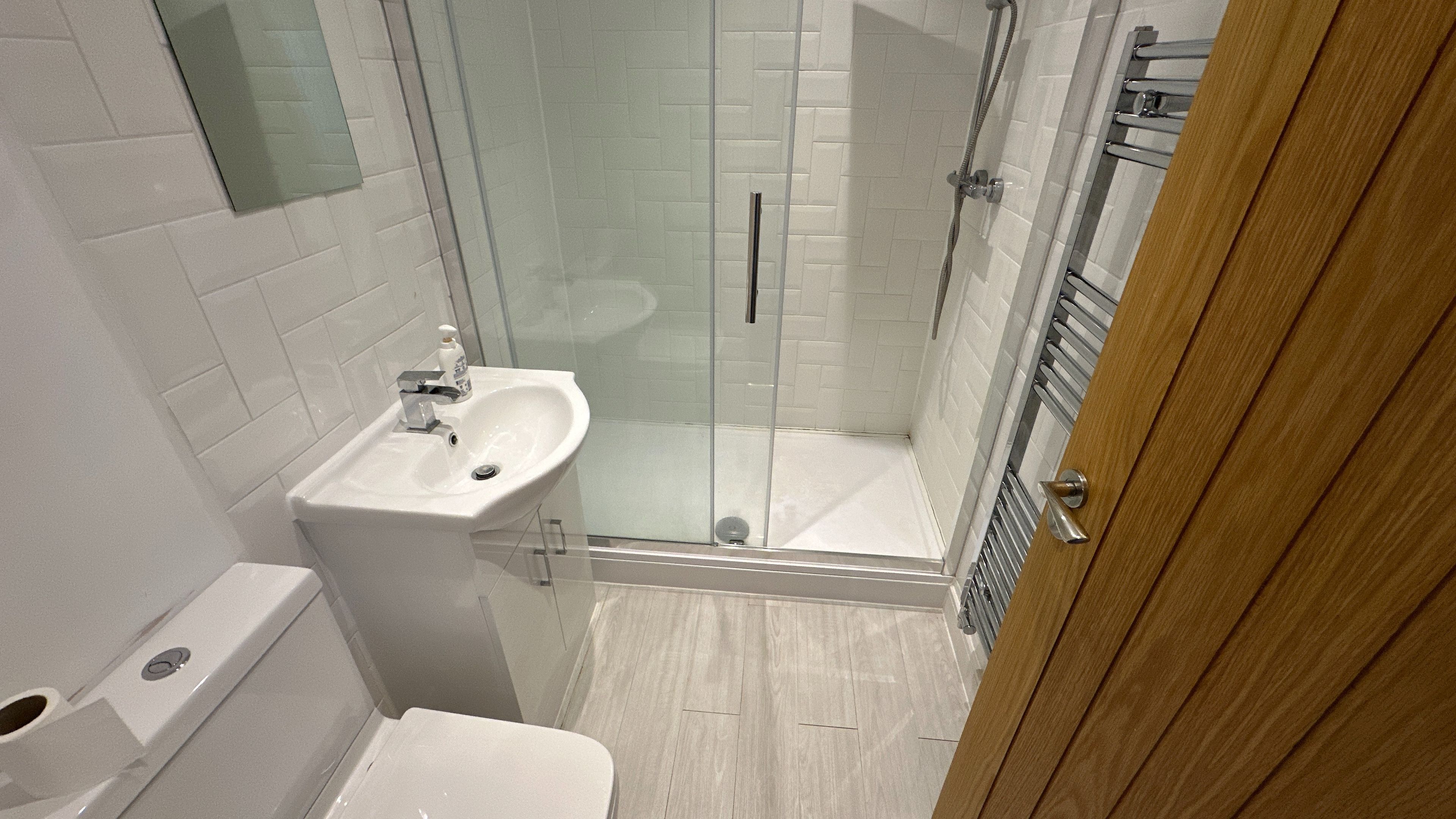 A bathroom with a glass-enclosed shower, a sink, and a toilet.