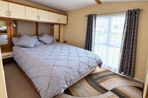 Ein Schlafzimmer mit Bett, Kleiderschrank und Blick ins Freie.
