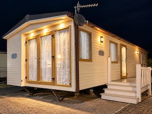 Ein Wohnmobil mit Veranda, Satellitenschüssel und einer Treppe, die zum Eingang führt.