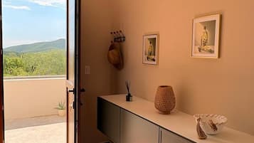 Una habitación con puerta corredera que da a un balcón, una encimera alargada con objetos decorativos y cuadros en la pared.