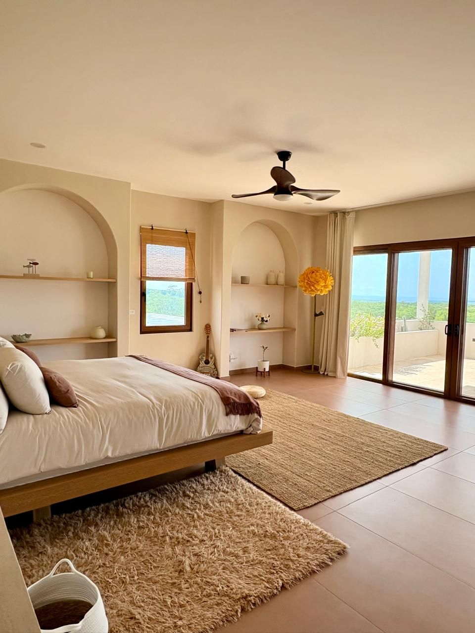Quarto com cama, ventilador de teto, janela e vista para o exterior.