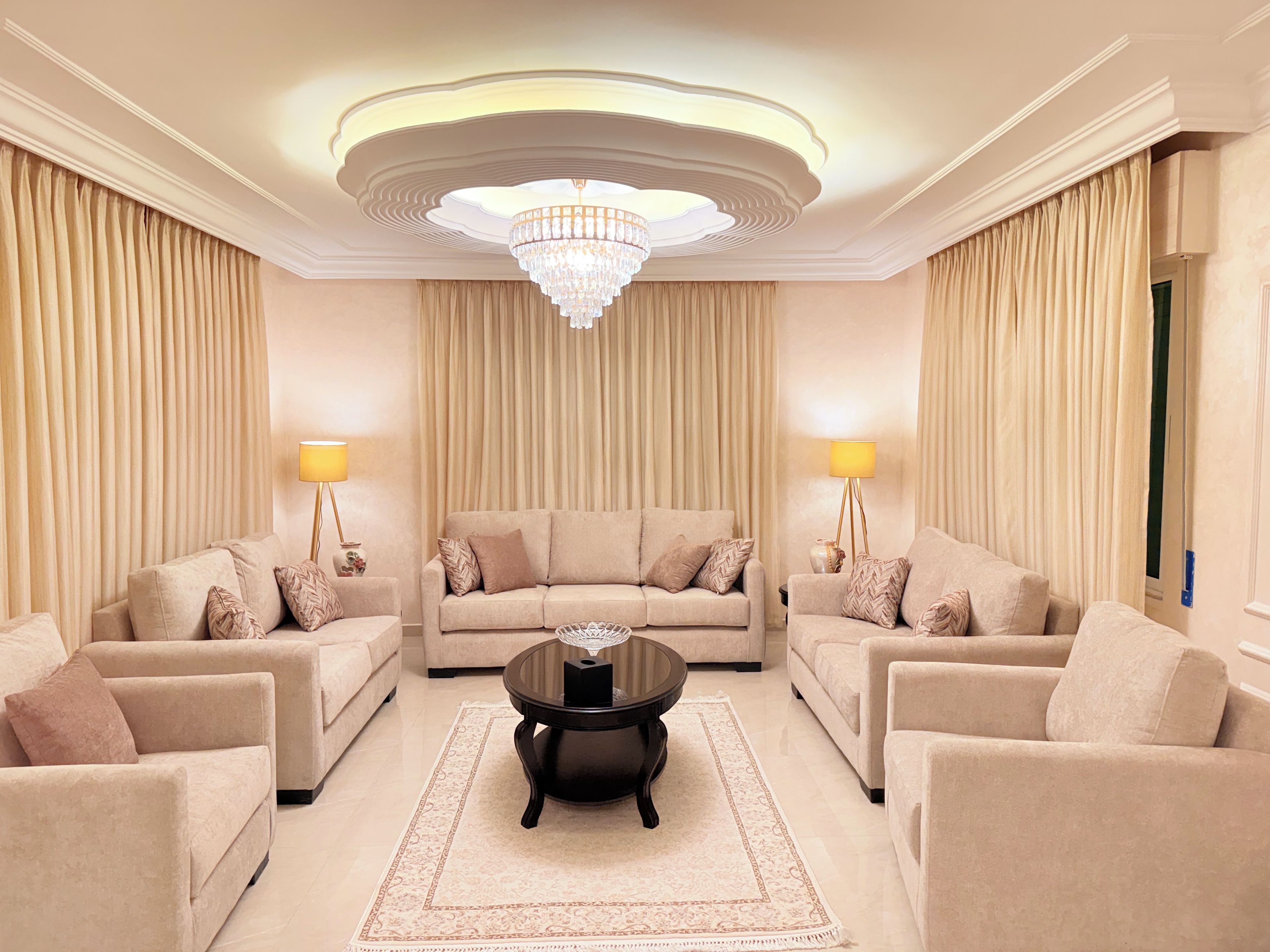 A spacious living room with a large chandelier, two sofas, a coffee table, and lamps.