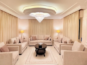 A spacious living room with a large chandelier, two sofas, a coffee table, and lamps.