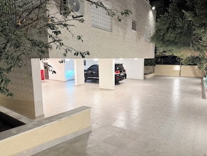 Un estacionamiento con un coche, un ventilador y un edificio con ventanas.