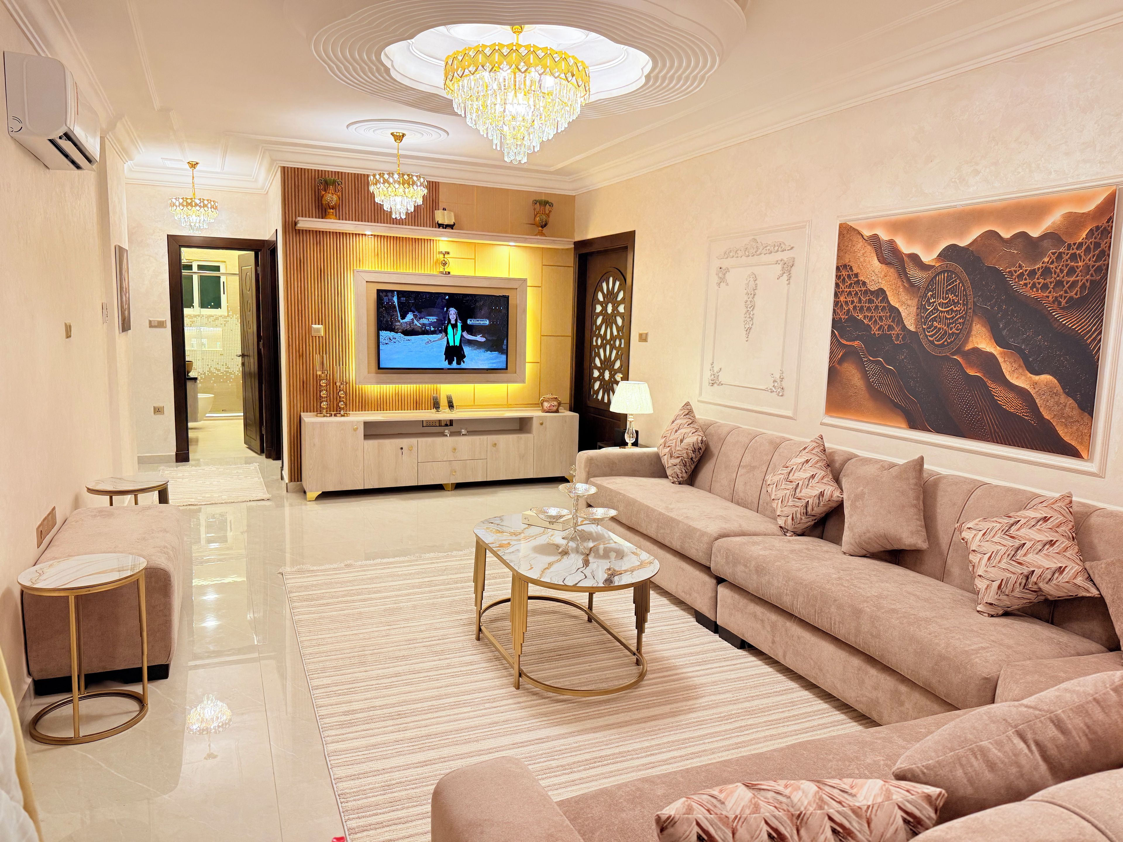 A modern living room with a television, sofa, coffee table, and decorative pillows.