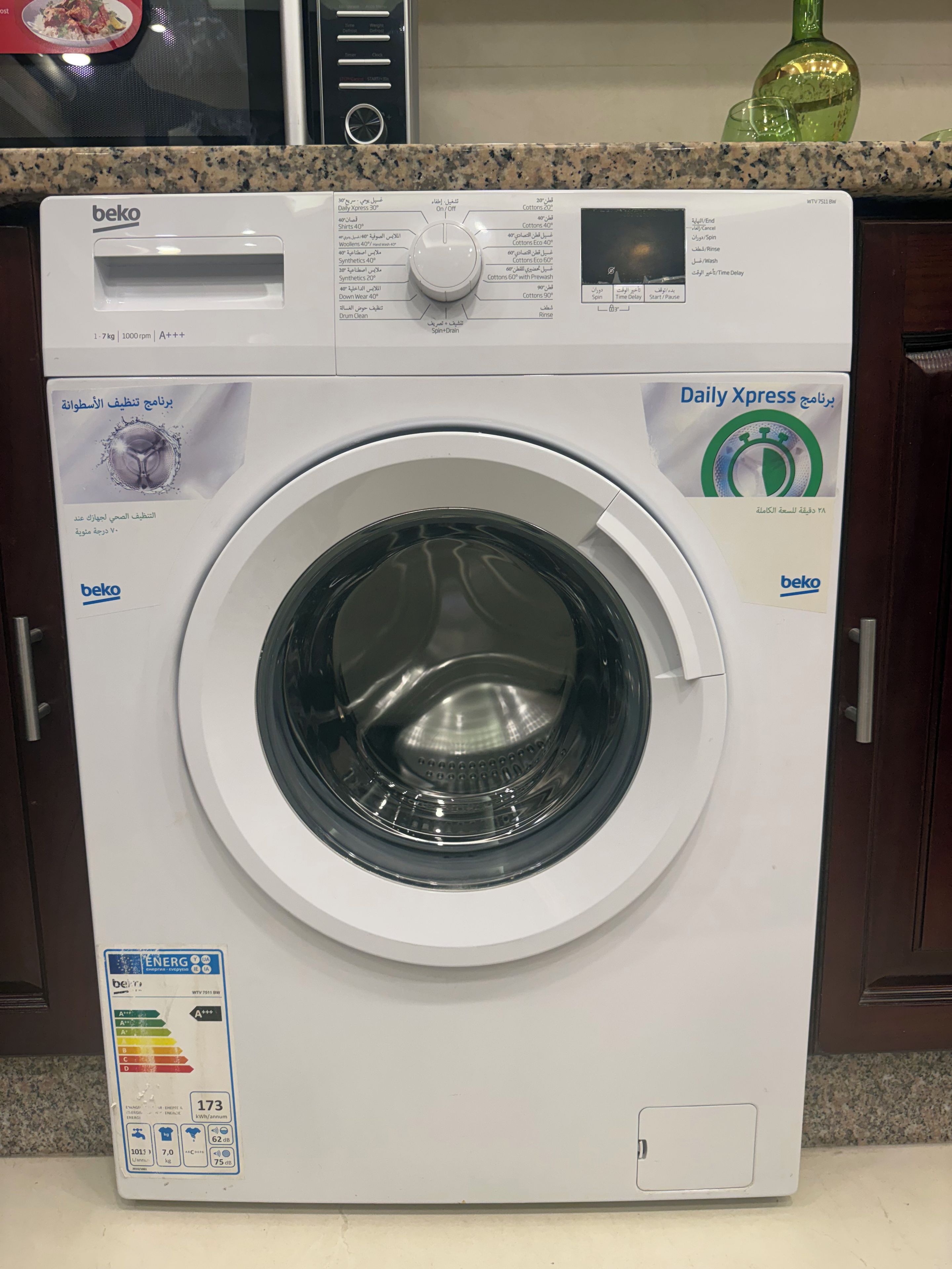 Eine Waschmaschine mit Frontlader, einer Bedienblende, einem Energieeffizienzlabel und einem Wasserstandsanzeiger.