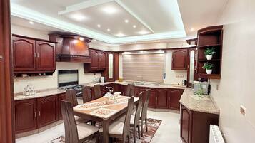 A modern kitchen with dark wood cabinets, a central island, and a dining area with chairs.