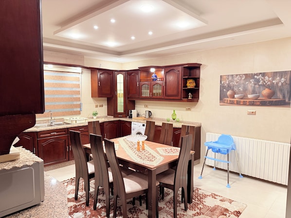 A modern kitchen with dark wooden cabinets, a granite countertop, and a dining area with a table and chairs.