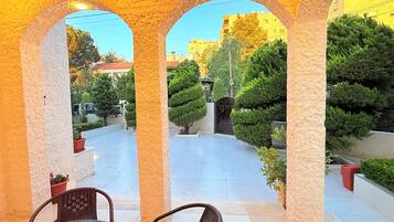 A covered outdoor area with stone arches, a tiled floor, and potted plants.
