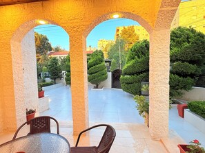 A covered outdoor area with stone arches, a tiled floor, and potted plants.