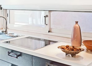 A kitchen with a built-in stove, a bowl of nuts, a vase, and a window with blinds. - Rialto - Bright Roof Studio (Venezia)