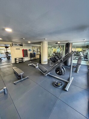 A gym with exercise equipment, benches, and a weightlifting area. - City View Apartment for 4 | Tressesenta Tower | Punta del Este (Punta del Este)