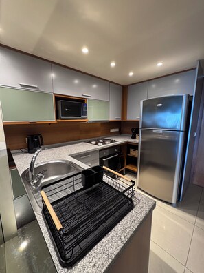 A modern kitchen with stainless steel appliances, a microwave, and a built-in oven. - City View Apartment for 4 | Tressesenta Tower | Punta del Este (Punta del Este)