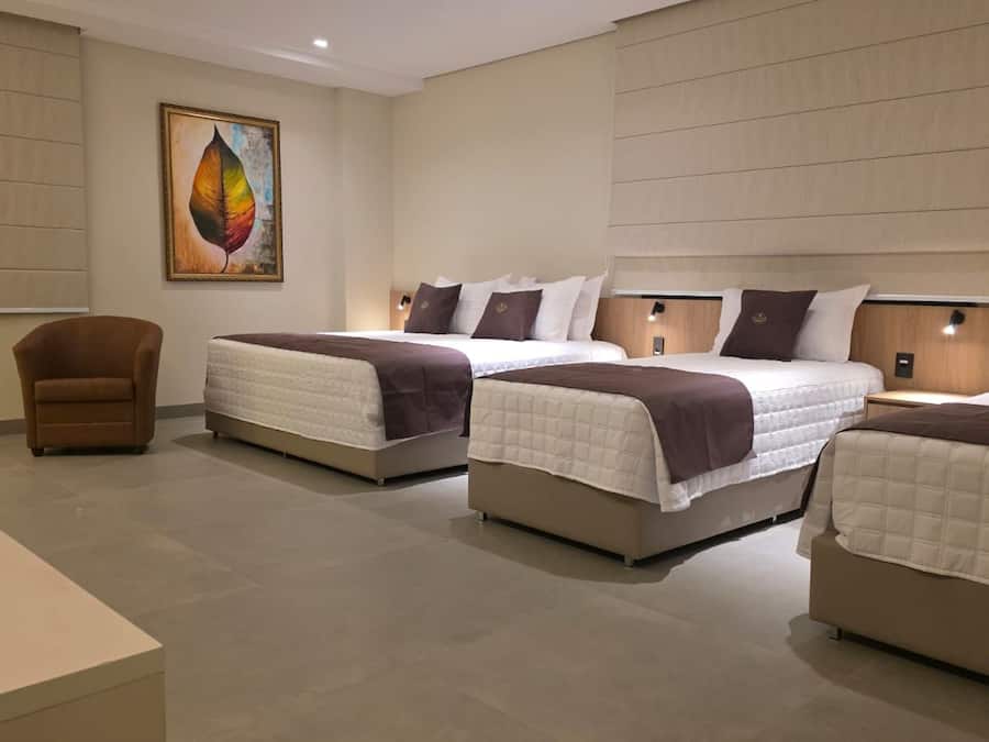Habitación de hotel con tres camas, un sofá y un cuadro en la pared.
