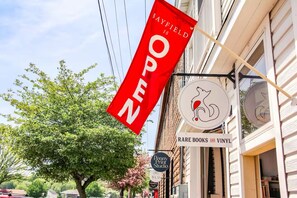 Ein Schaufenster mit einem roten Banner, auf dem 'BAYFIELD IS OPEN' steht, und darunter ein Schild für 'RARE BOOKS AND VINYL'.