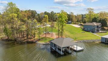 A lakeside property with a dock, a small house, and a larger building with a porch.