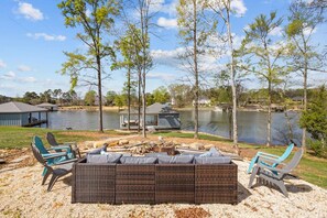 Un espace extérieur aménagé au bord du lac, avec des bancs et des fauteuils intégrés, entouré d’arbres et offrant une vue sur le lac.