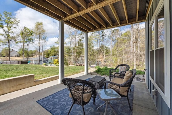 An outdoor patio with a covered seating area, a view of the surrounding landscape, and a clear sky.