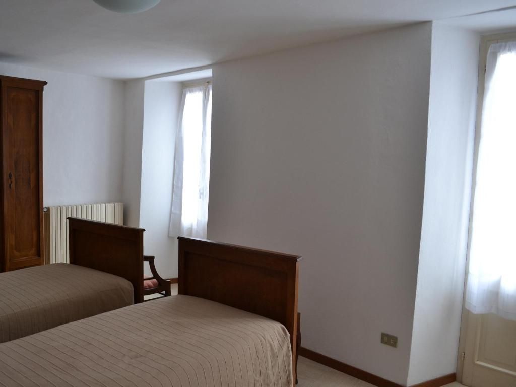 Ein Schlafzimmer mit zwei Betten, einem Holzschrank, einem Heizkörper und einem Fenster mit Vorhängen.