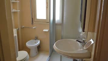 Ein Badezimmer mit Toilette, Bidet und Waschbecken mit Spiegel.