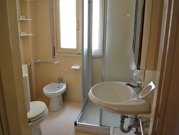 Un baño con inodoro, bidé y lavabo con espejo.