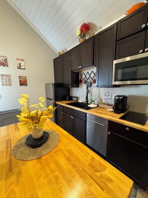 A kitchen with dark cabinets, a wooden countertop, a stainless steel dishwasher, and a microwave. - 9139 Orange -2-bedroom w/ Loft - Melton Hill Lake & Marina -Close to downtown UT (Oak Ridge)