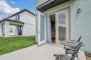 Ein Wohnhaus mit Terrasse, einer Schiebetür und einem kleinen Tisch mit Stühlen im Freien.
