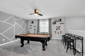 A room with a pool table, a ceiling fan, and a bar area with stools. - Anazing new 5BR / 3 bath    2131 Derwent Dr (Davenport)
