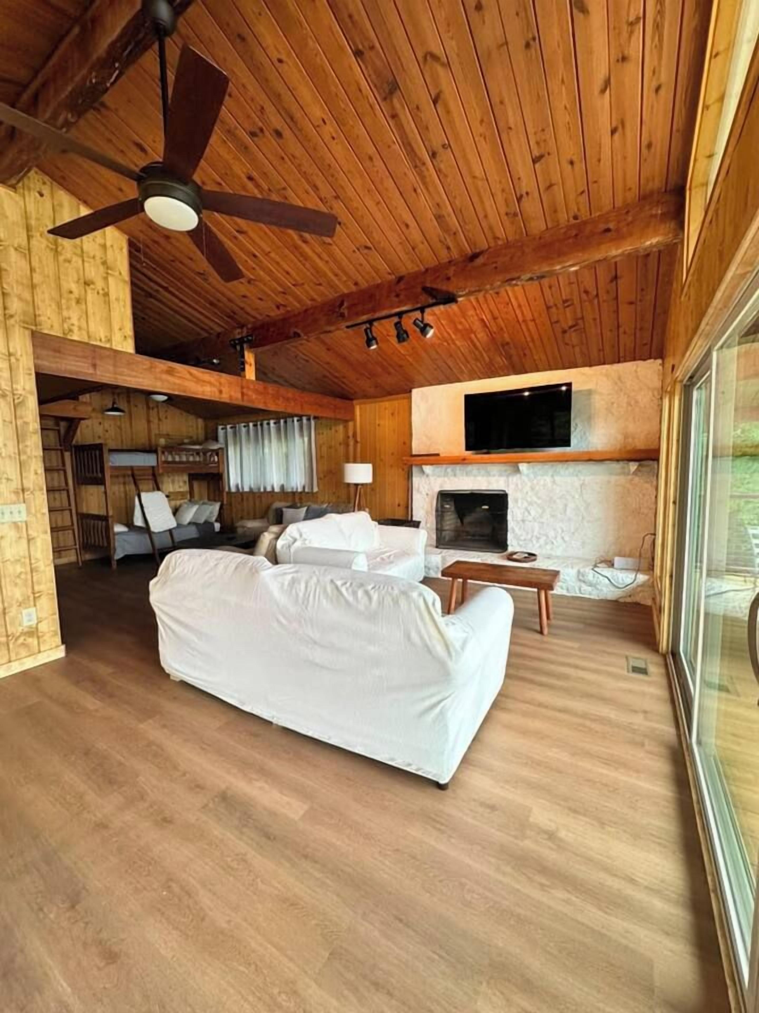 Quarto com uma cama grande, lareira, televisão e ventoinha no teto.