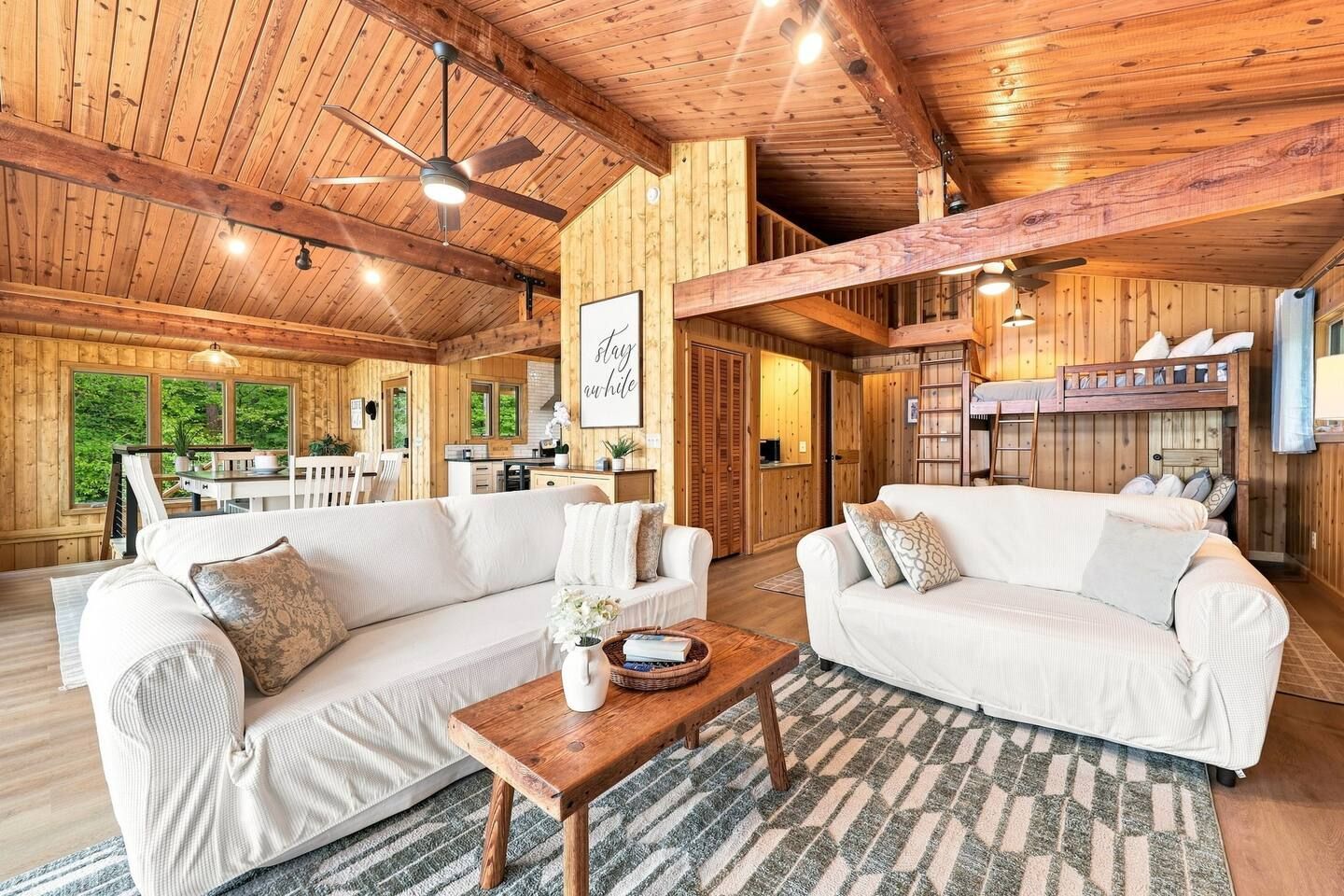 Guests can stretch out on one of the two cozy sofas to unwind, with a ladder leading up to the loft above.