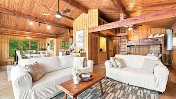 Guests can stretch out on one of the two cozy sofas to unwind, with a ladder leading up to the loft above.