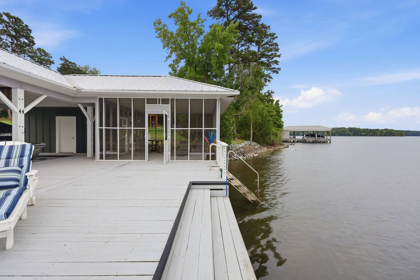 A waterfront property with a covered deck, a boat dock, and a view of the lake.