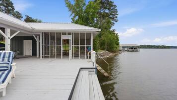 A waterfront property with a covered deck, a boat dock, and a view of the lake.
