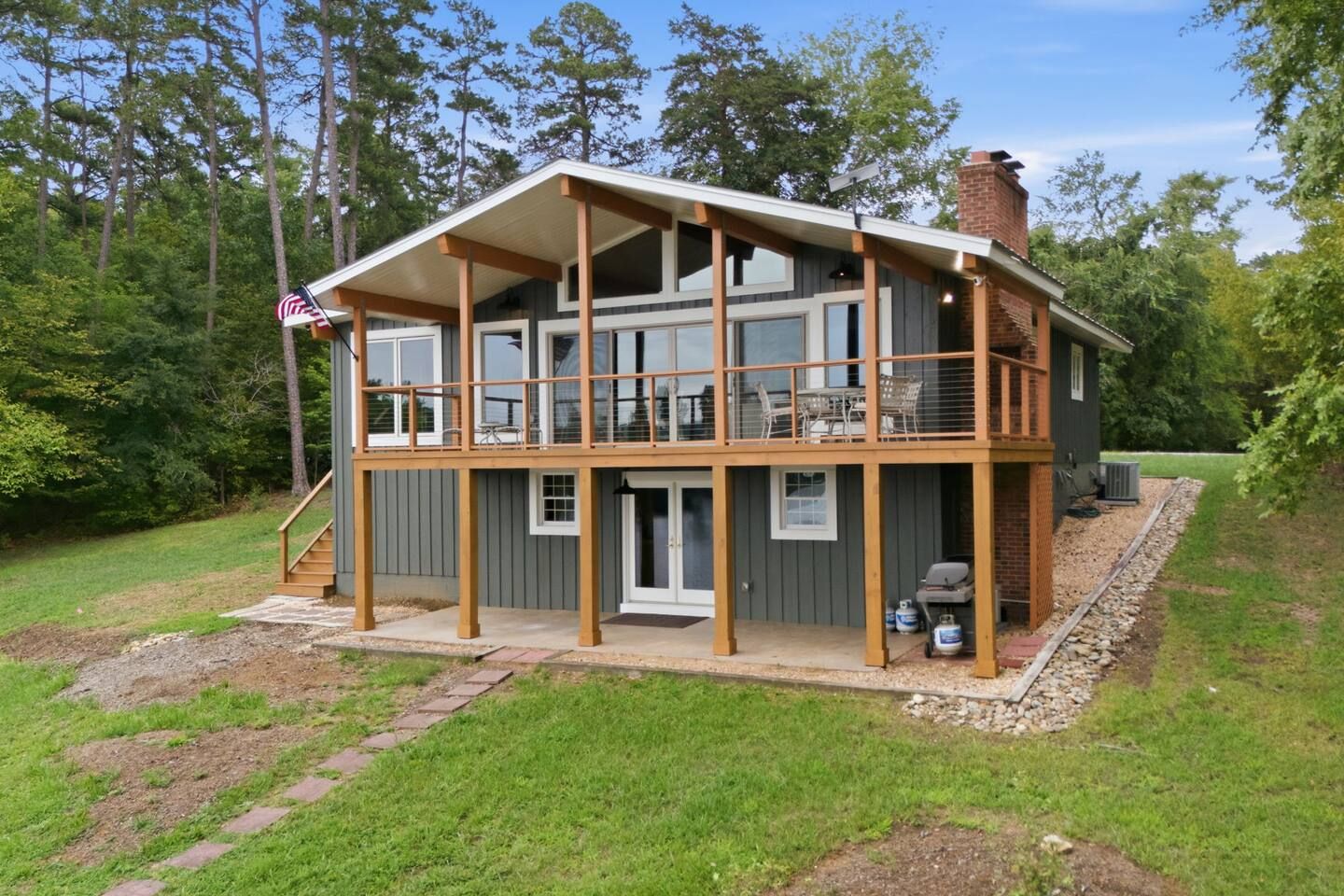 A two-story house with a covered porch, a chimney, and a flag.