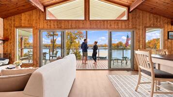 Guests can sink into the cozy sofa and dining table in this sunroom, taking in wide-open lake views through the wall of windows and doors to the deck.