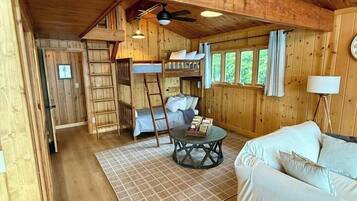 A wooden interior with a bunk bed, a sofa, a coffee table, and a lamp.