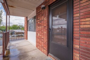 A residential building with a brick exterior, a large sliding glass door, and a covered porch area.