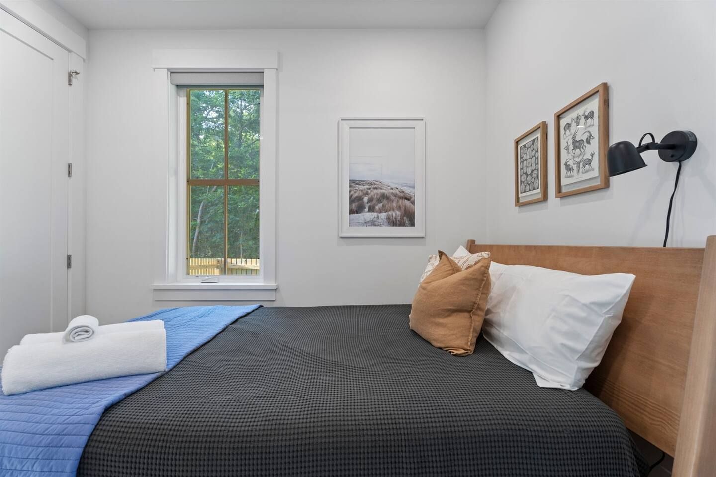 Une chambre à coucher avec un lit, une fenêtre et des œuvres d’art accrochées au mur.
